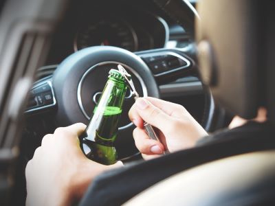 person with alcoholic beverage at wheel of vehicle