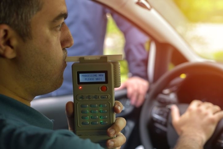 man blowing into a breathalyzer