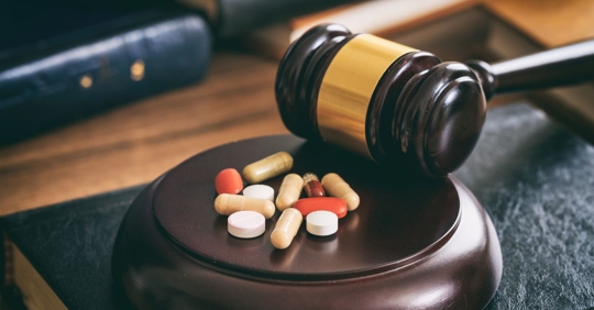 Gavel next to colorful pills