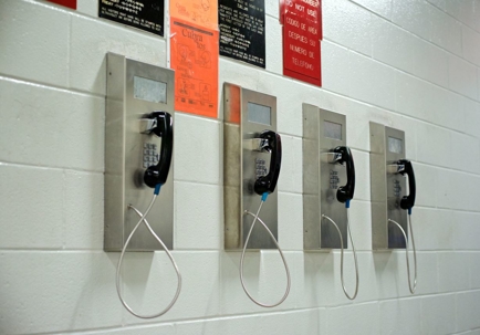 4 pay phones lined up on a jail wall